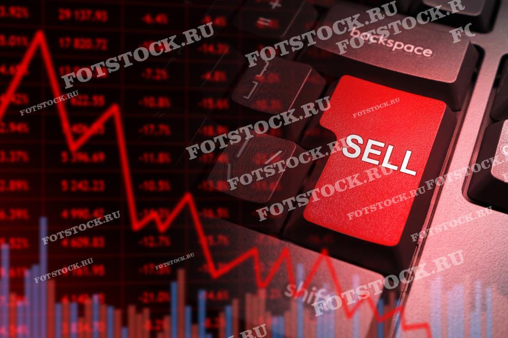 На фотографии изображена красная клавиша "Sell" на клавиатуре, наложенная на фон с графиком, демонстрирующим падение рынка. Снимок символизирует финансовый кризис, продажу активов и биржевые операции в условиях спада.